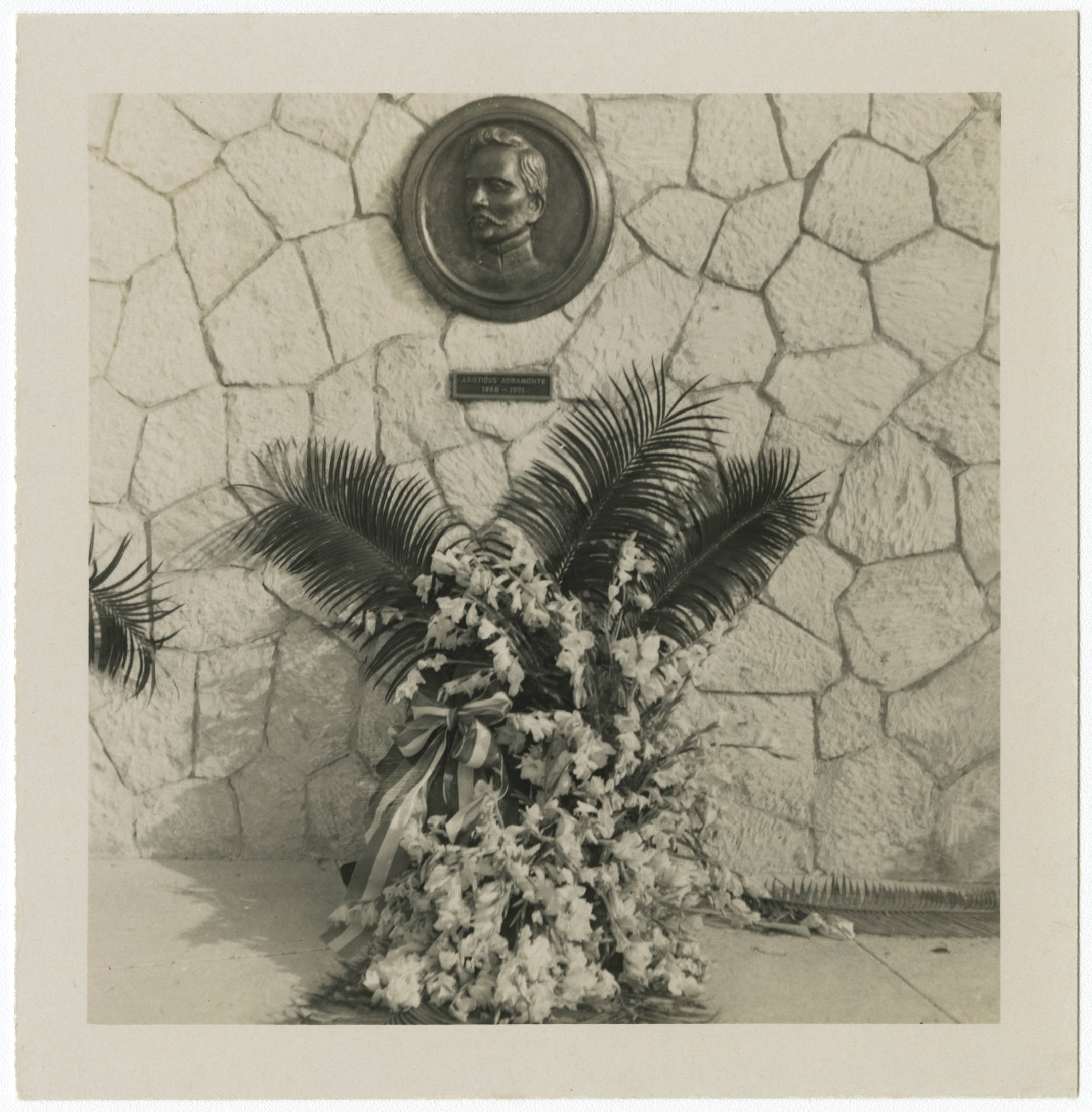 Bronze plaque of Dr. Aristides Agramonte and floral arrangement at the Monumento Nacional Campamento Lazear (Camp Lazear's National Monument) in Marianao, Cuba — Anónimo