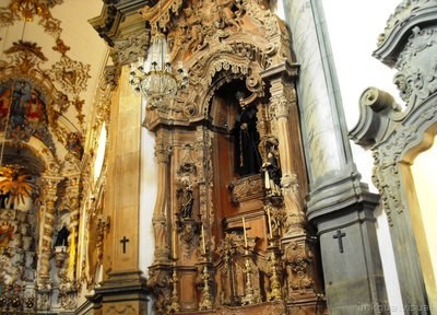 Interior de iglesia barroca colonial con retablo dorado y esculturas.