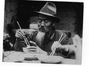 Hombre asiático con barba comiendo con palillos — Fotógrafo anónimo (La Habana, s. XX)