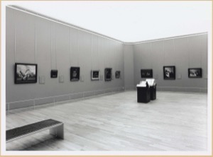 Sala de museo con obras expuestas y banco — Anónimo